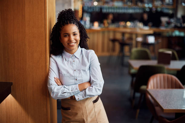 istock Happy black waitress with arms crossed looking at camera. 1411158568