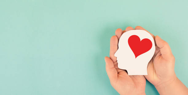 Holding a head with a red heart in the hands, symbol of love and positive emotion, charity and support stock photo
