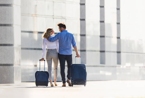 istock back view of business couple talking while pulling their suitcases on the street. 1411159472