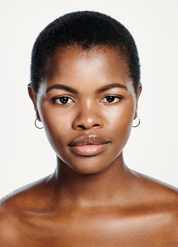 Face of a beautiful Afro woman with minimal makeup isolated on studio background, Portrait of one young beauty model with moisturized glowing and flawless looking skin posing for hygiene and skincare