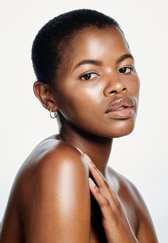 Face off a beautiful young African woman with healthy skin, isolated on a white background. Portrait of a serious lady embracing natural hair and beauty with good skincare products