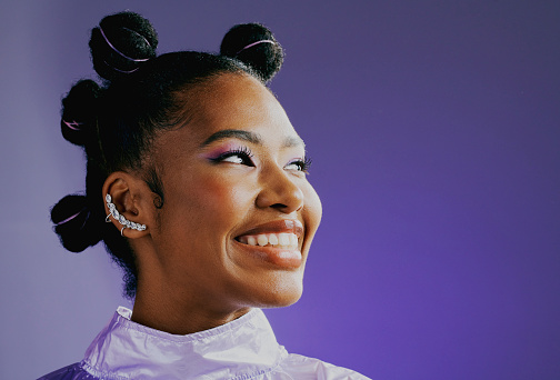 African American woman looks to the side smiling. Sporty young lady with funky hair and piercings grinning in happiness. Fashion model poses for hip and trendy store catalogue.
