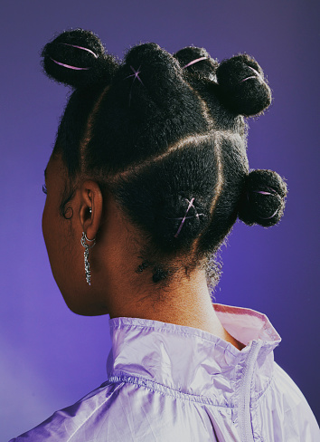 Mujer negra de pie sobre un fondo de estudio púrpura y mostrando su nuevo peinado moderno y funky desde atrás. Una mujer mostrando la parte posterior de su cabeza con un peinado creativo y elegante photo