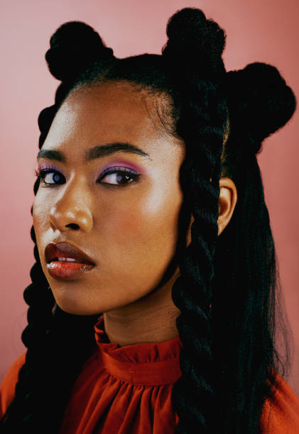 retrato de una joven vanguardista con maquillaje púrpura de moda y ropa naranja con un peinado de moda sobre un fondo de estudio. mujer segura de sí misma con personalidad audaz y actitud fría - braided fotografías e imágenes de stock