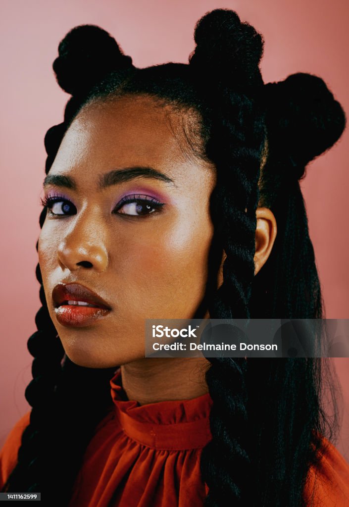Portrait of an edgy young woman wearing fashionable purple makeup and orange clothes with a trendy hairstyle against a studio background. Confident female with bold personality and cool attitude One Woman Only Stock Photo