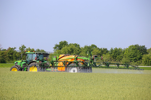 Farmer drives his tractor with crop protection sprayer over his wheat field to combat brown rust and mildewFarmer drives his tractor with crop protection sprayer over his wheat field to combat brown rust and mildew (Hockenheim Germany, May 14, 2020)