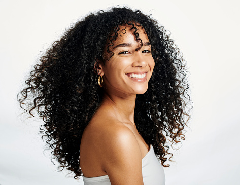 Beauty portrait of a black woman with an afro and glowing skin isolated against a white background in studio with copy space. Beautiful young female with a perfect and flawless skincare routine