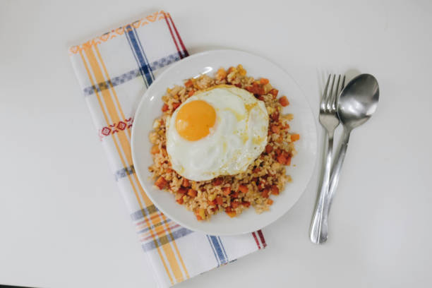 Vegetable Fried Rice with a sunny side up on a White Plate on the White Background Directly Above Photo.
