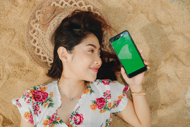 istock A young beautiful Asian woman lying on the sand while showing phone screen 1411169018