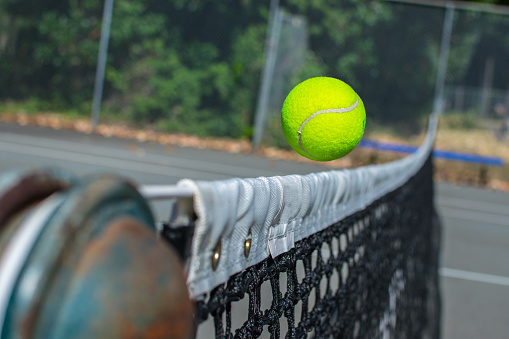 A tennis ball barely makes it over the net