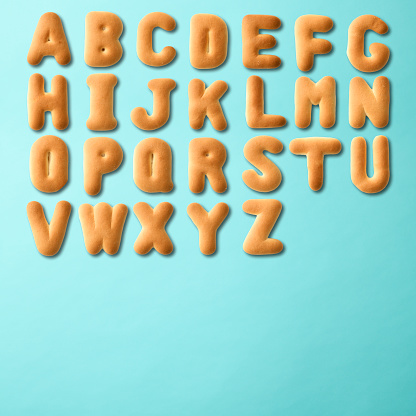 Overhead shot of capital letter alphabetical order in cookies on light blue background with copy space.