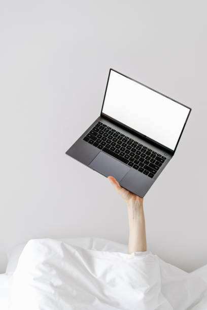 istock Person laptop when staying in bed with fresh white linens 1411172408