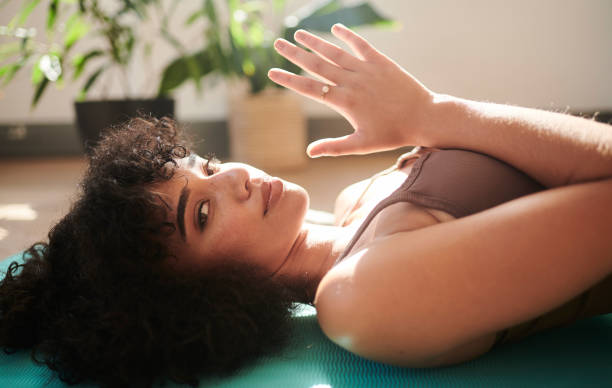 Portrait de dame sur un tapis dans un studio de yoga pendant un cours de yoga en intérieur. Jeune femme pratiquant un exercice de méditation dans un centre de remise en forme. Afro-américaine gardant son esprit et son corps en forme avec sa routine de y