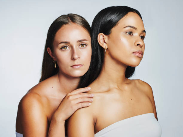 istock Two serious women isolated against grey studio background and showing diverse feminine unity and pride. Models and friends with fresh, clean and hydrating skincare routines for dewy and glowing look 1411177337
