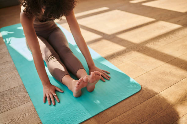 istock A woman stretching and meditating while practicing yoga at home with copy space from above. Calm, relaxed and focused female working out quietly for inner peace and zen energy on an exercise mat 1411177926