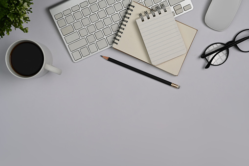 Above view magnifying glass, financial document, notebook and glasses on white office desk.