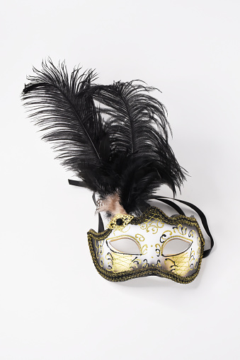 Pretty venetian golden carnival mask with feathers isolated on a white background