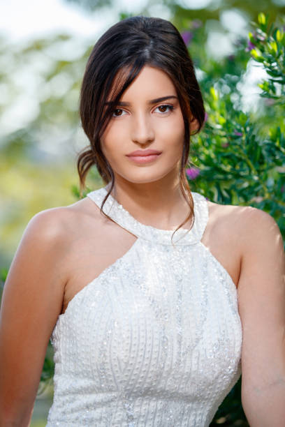 istock Beautiful young brunette in white sleeveless top looking at camera 1411179366