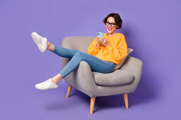 istock Portrait of attractive cheerful girl sitting using device communicating having fun rest isolated over violet lilac color background 1411179442