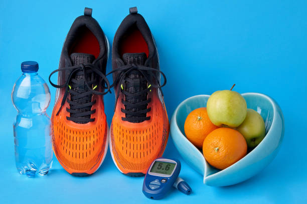 zapatillas naranjas, glucómetro, botella de agua potable y frutas sobre fondo azul - diabetes blood sugar test insulin healthy eating fotografías e imágenes de stock