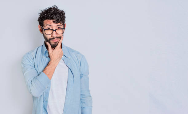 Handsome man rubbing his beard with a doubtful expression, Person rubbing his chin with a doubtful expression. handsome bearded man with doubt expression isolated