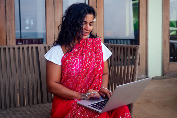 indian beautiful businesswoman working on a modern laptop in the cafe restaurant on the shore of the paradise ocean.Web Designer girl freelancer in india in the sea .remote work ,concept copywriter stock photo