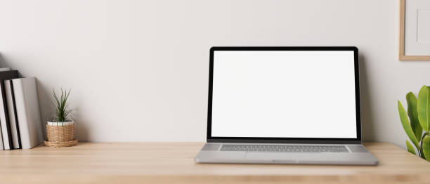 istock Minimal working desk with opened notebook laptop mockup over white wall. 1411182211