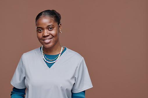 Portrait of African young social worker in uniform smiling at camera isolated on beige background