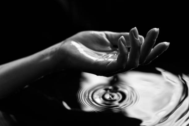 Woman's hand and water splashing on it. Black and white