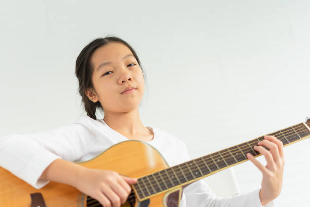 istock beautiful young children playing guitar with copy space, look at camera. asian children study and learn musical and singing in education classroom at small school 1411187771