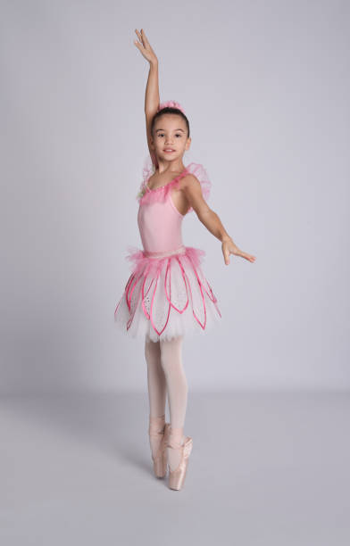 istock Beautifully dressed little ballerina dancing on grey background 1411189379