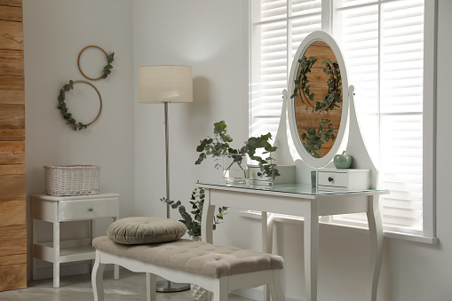 Stylish dressing table decorated with beautiful eucalyptus branches indoors