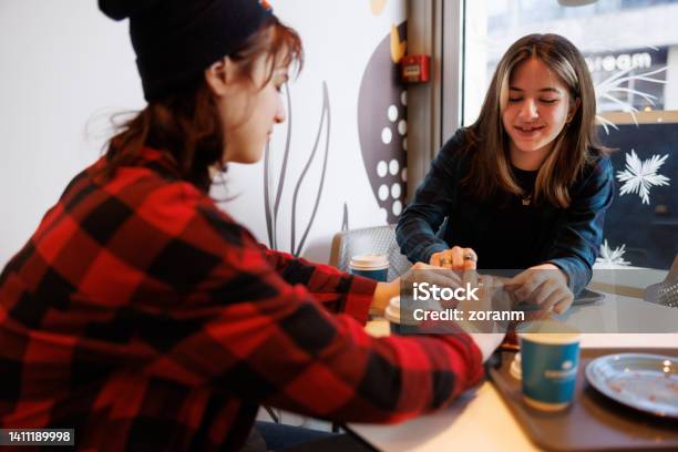 Teenage Girls Enjoying Street Food And Coffee Inside Stock Photo - Download Image Now