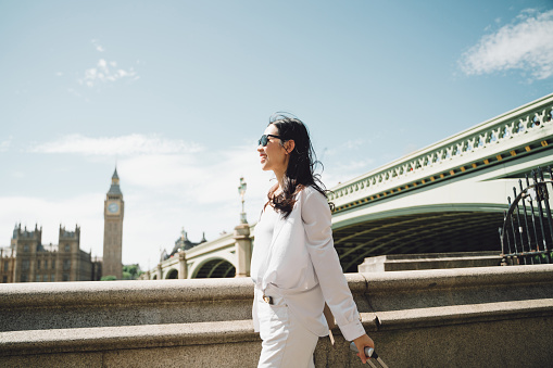 UK, London, Asian beautiful woman walking with her luggage in front of Big Ben.