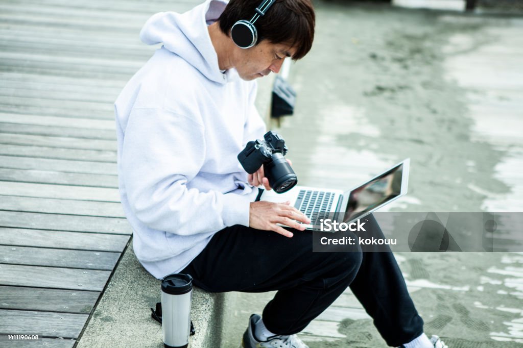 Male video creator is working at the beach. A man sitting on a seaside terrace.
He is wearing headphones.
A creator who edits video using a laptop. Japan Stock Photo