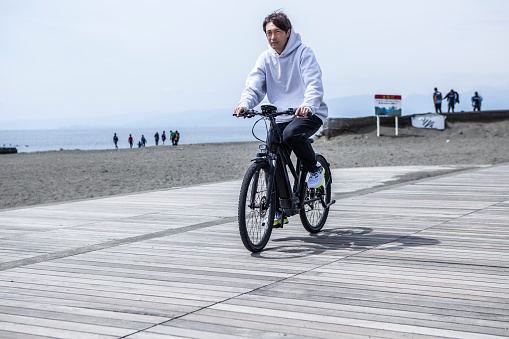 A 40s Japanese man riding bicycle on a beachside terrace .