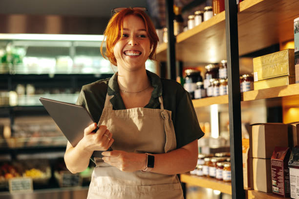 Cheerful grocery store owner smiling in her shop stock photo