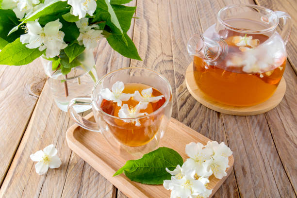 istock tea composition on a rustic wooden table. a cup of jasmine tea on a tray, a teapot with freshly brewed tea and a glass jar with a branch of jasmine. 1411194731