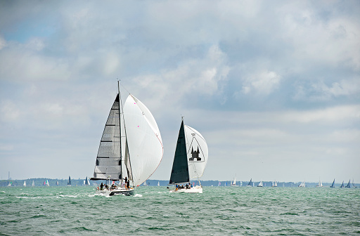 Yachts racing downwind during Yarmouth Regatta, The Solent, England. Competitive yacht racing is a feature of The Solent, where different classes of sailing boat compete against one another on set courses that bring the craft into close proximity, especially when yachts under spinnaker on a downwind run cross those on a beat on the opposite leg.