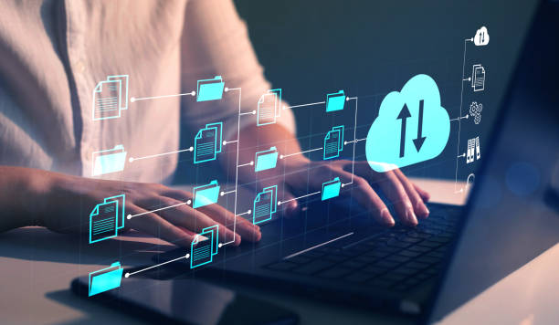 A person is using a laptop with hands on the keyboard, surrounded by a digital interface displaying icons of folders and a cloud symbol with arrows indicating data transfer, set against a dark background.