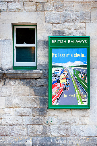 Railway travel poster, Corfe Castle station, Dorset, England. Summer in Britain brings out the colours of the countryside and sunlight lifts the hues and shades of natural stone and architecture in the quaint and tranquil villages of England