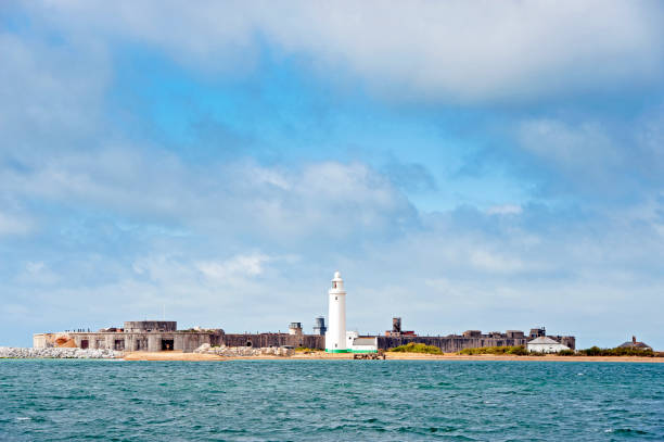 Hurst Castle and lighthouse, Western Solent, England. On a windy and tide beaten sand and shingle spit promontory, Hurst Castle protects and defends the Needles passage to The Solent from attack and invasion and has done from its inception by Henry Vlll through both Napoleonic and 2nd World Wars