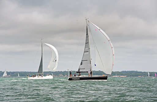 Yachts racing under spinnaker downwind  during Yarmouth Regatta, The Solent, England. Competitive yacht racing is a feature of The Solent, where different classes of sailing boat compete against one another on set courses that bring the craft into close proximity, especially when yachts under spinnaker on a downwind run cross those on a beat on the opposite leg.