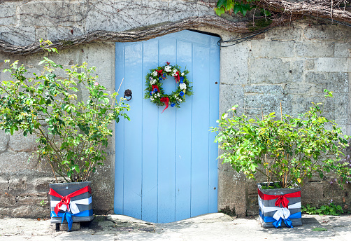 Wooden cottage door and floral decoration, Corfe Castle, Dorset, England. Summer in Britain brings out the colours of the countryside and sunlight lifts the hues and shades of natural stone and architecture in the quaint and tranquil villages of England