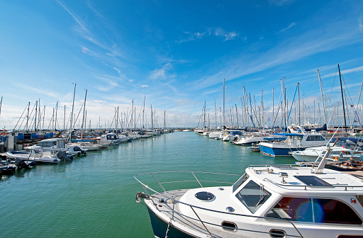 Regatta yachts fill the berths under a sunny blue sky along the pontoons in Yarmouth harbour marina before their racing weekend along the Solent, seen from the harbour side, Yarmouth, Isle of Wight, England