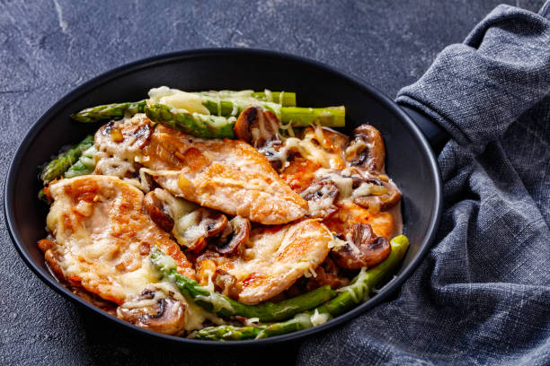 Chicken Madeira in frying pan, top view Chicken Madeira, juicy chicken breasts and mushrooms in a madeira cream sauce under melty mozzarella cheese and asparagus in  frying pan madeira sauce stock pictures, royalty-free photos & images
