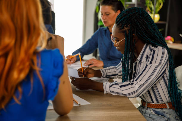 istock Diligent businesswoman writing notes during a project meeting with her colleagues 1411201897