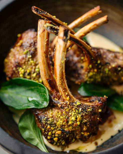 Roasted rack of lamb dish with herbs and sauce Closeup on roasted gourmet rack of lamb dish with herbs and sauce rack of lamb stock pictures, royalty-free photos & images