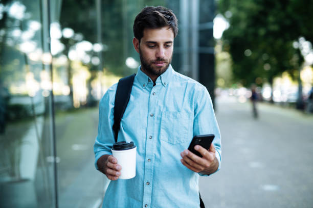 istock Adult man using smart phone on the go, drinking coffee on the way to work 1411202745