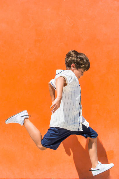 istock Child jumping on an orange background. 1411203766